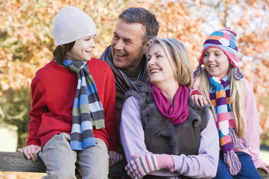 Happy family of four dressed in winter clothes enjoying time outdoors.